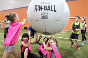 Children playing Kin Ball indoors, showcasing teamwork and fun during a recreational activity, highlighting ZOVB Singapore's party package offerings.