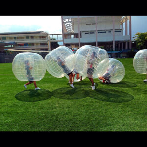 Participants in inflatable bubbles playing on a grassy field