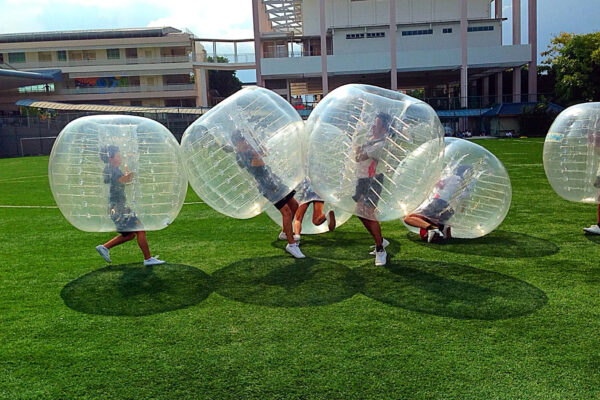 Participants in inflatable bubbles playing on a grassy field