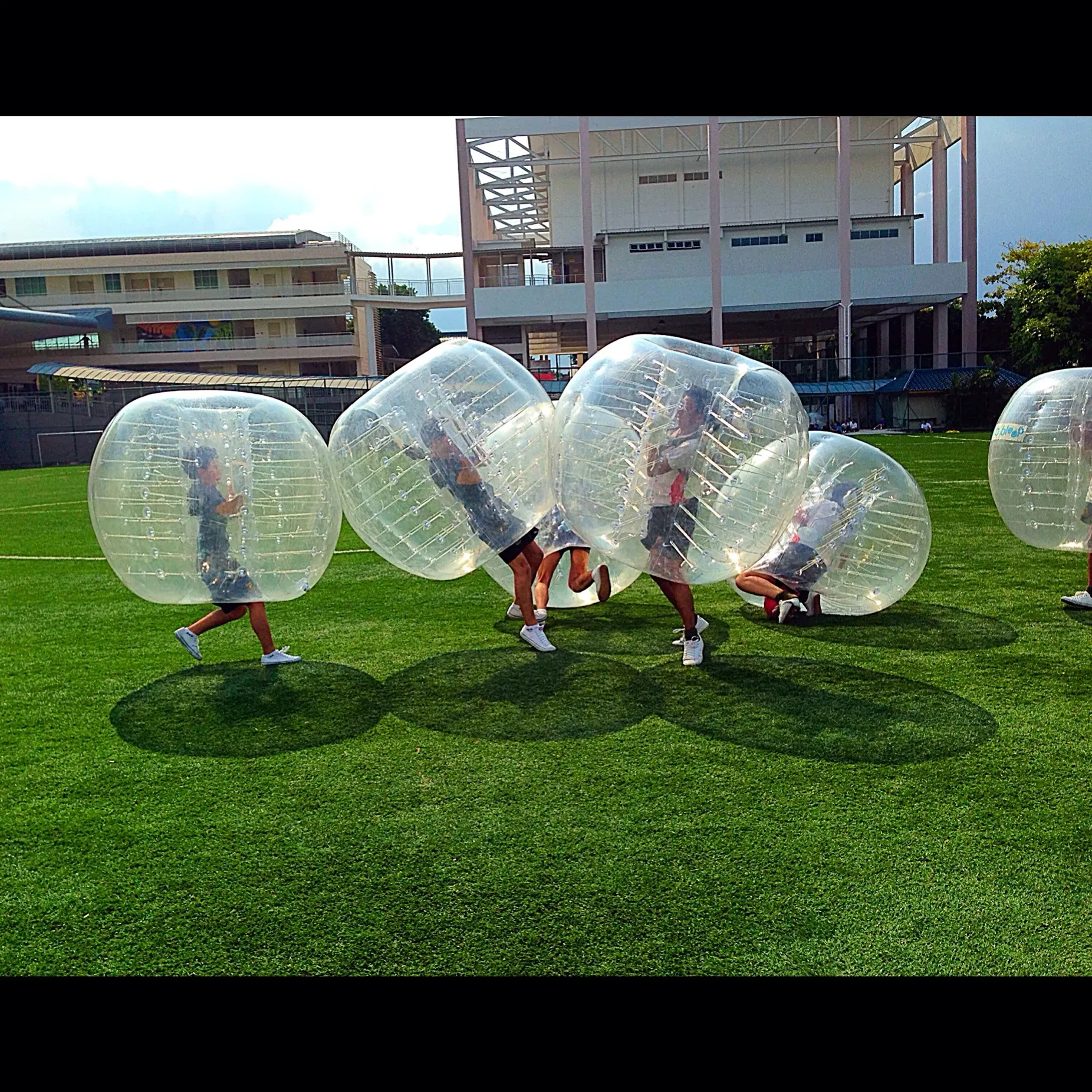 Participants in inflatable bubbles playing on a grassy field