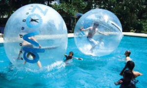 Children playing inside inflatable water balls in a swimming pool